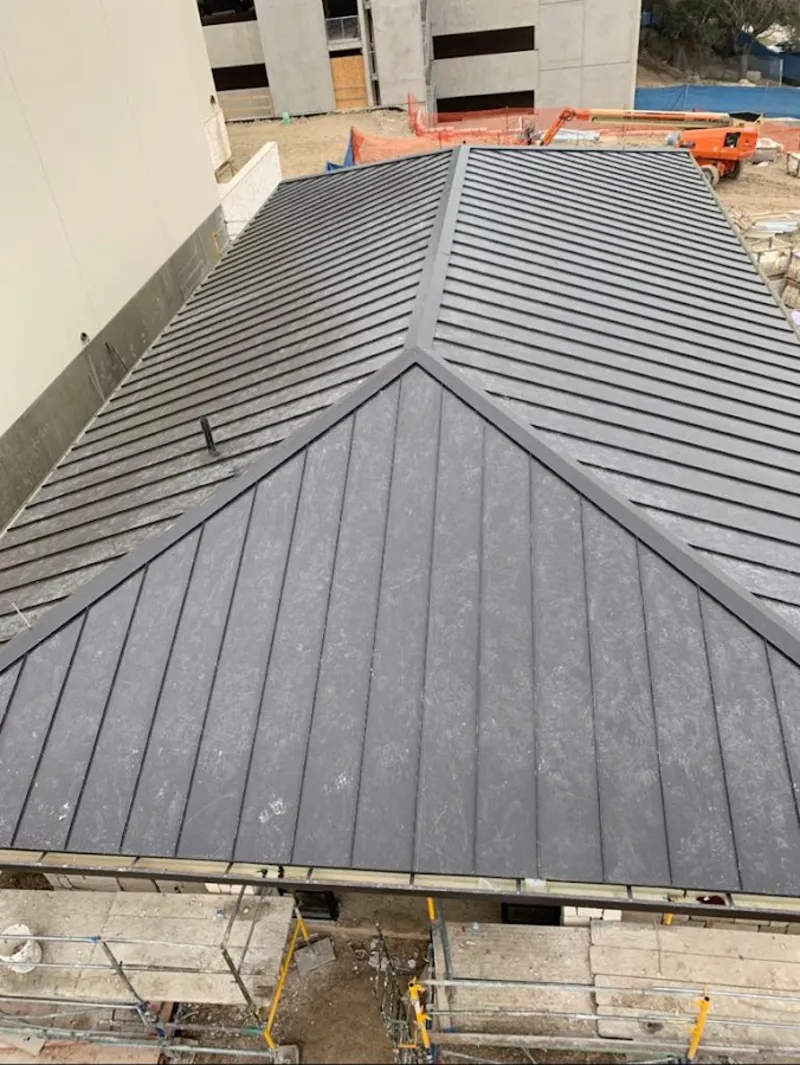 Commercial metal roof construction with crane equipment in Lenox